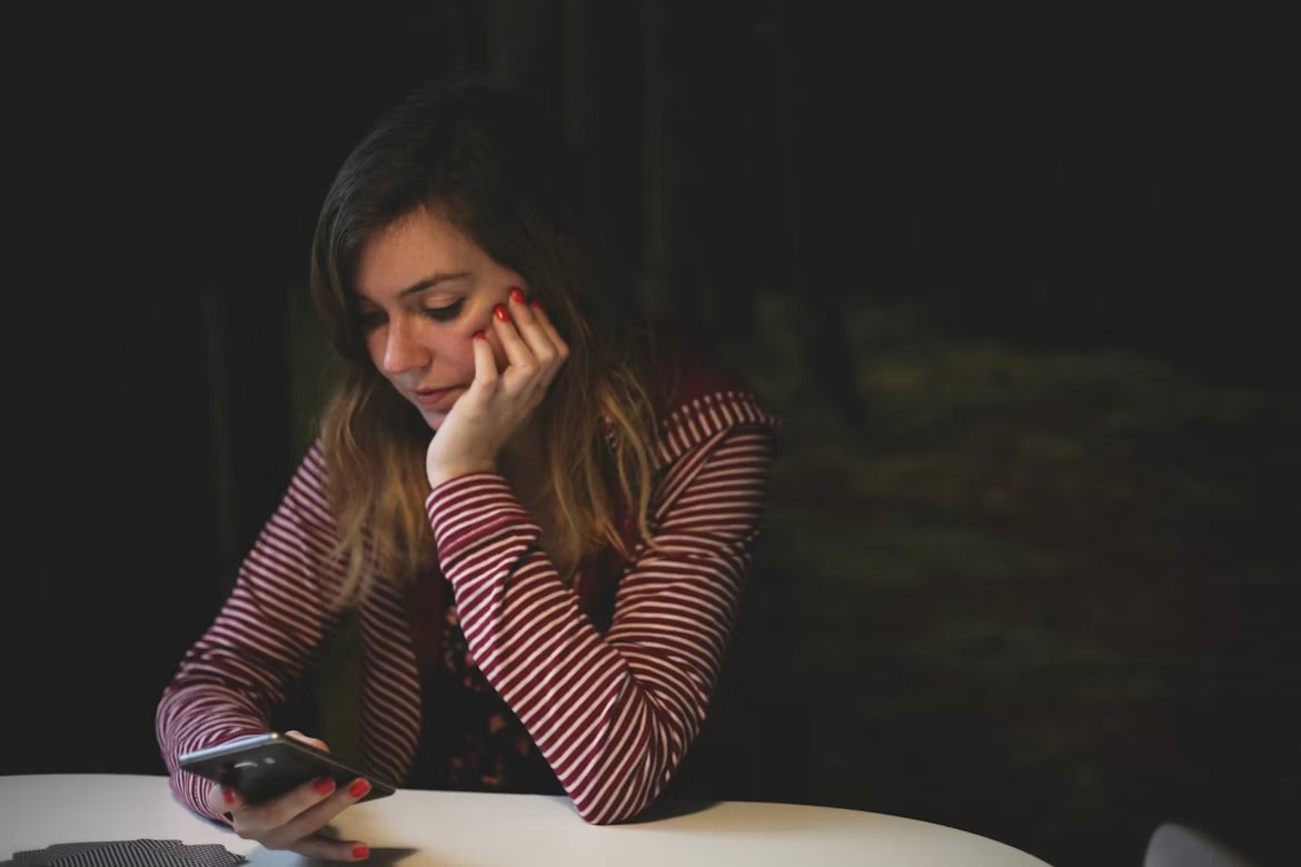 A woman reading support on her phone in the evening
