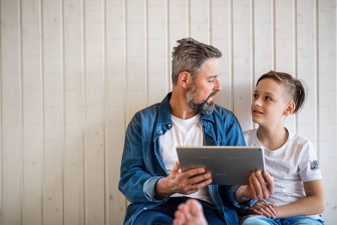 A father and son looking at a tablet together
