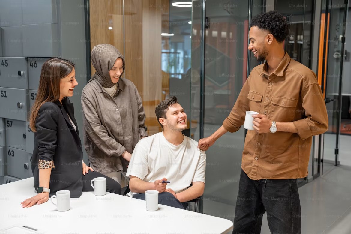 Colleagues laughing together over coffee in a modern office