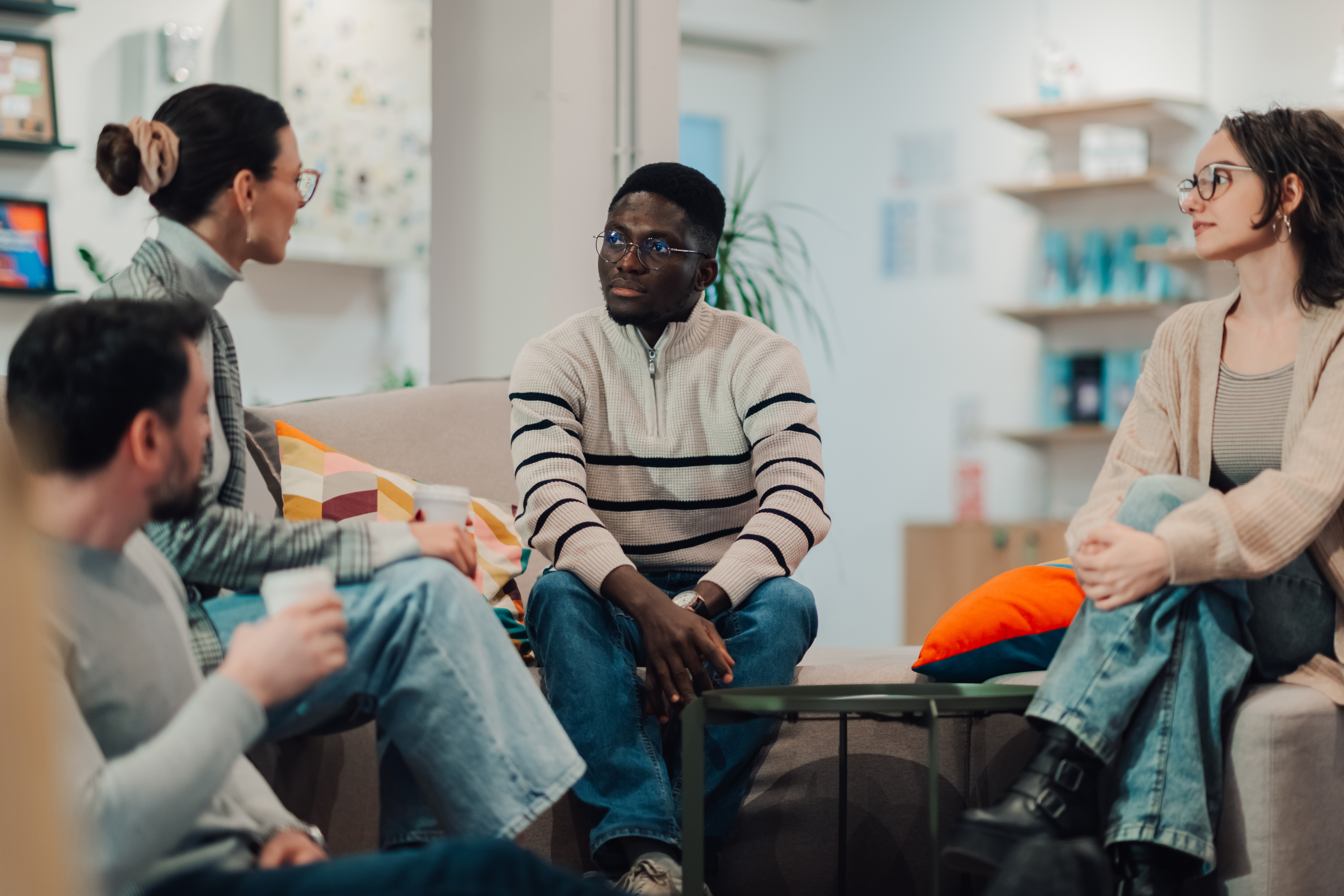 A support group of colleagues talking together on sofas